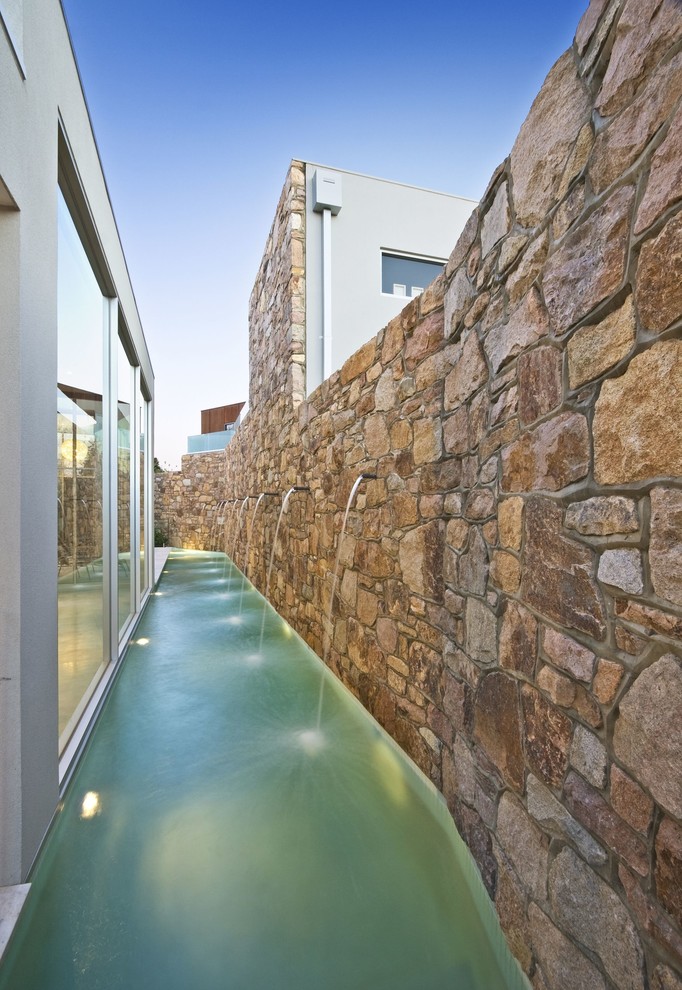 Photo of a small contemporary side custom shaped lengths swimming pool in Melbourne with natural stone paving.