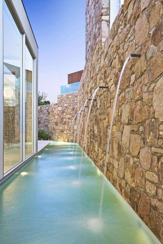 Immagine di una piccola piscina monocorsia design personalizzata nel cortile laterale con pavimentazioni in pietra naturale