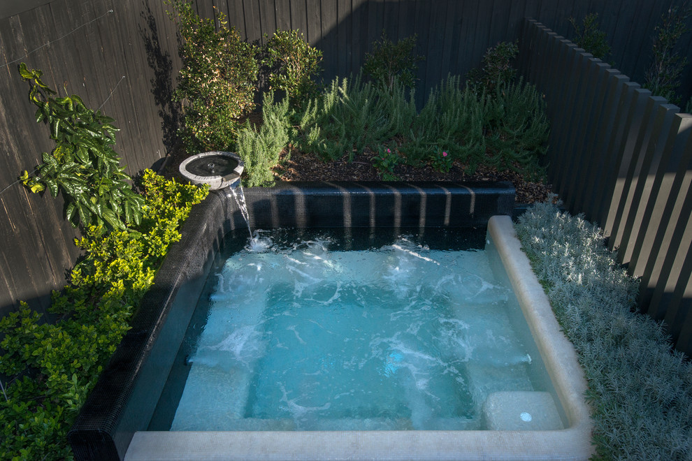 Immagine di una piccola piscina costiera personalizzata dietro casa con una vasca idromassaggio e piastrelle