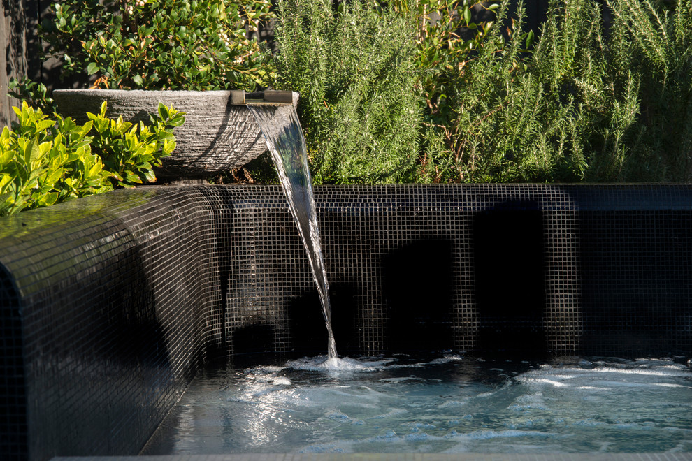 Immagine di una piccola piscina minimal personalizzata dietro casa con una vasca idromassaggio e piastrelle
