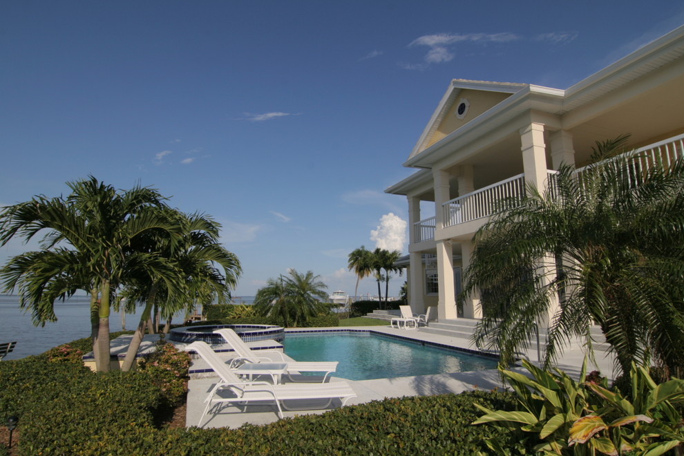 Ejemplo de piscinas y jacuzzis naturales clásicos grandes rectangulares en patio trasero con losas de hormigón