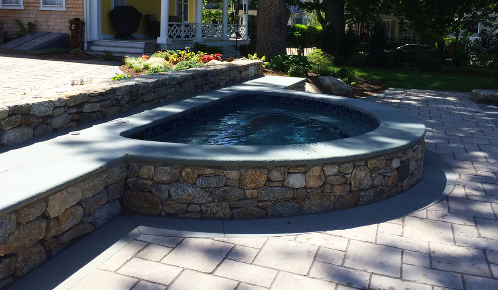 Photo of a large traditional back custom shaped swimming pool in Providence with a water feature and concrete paving.