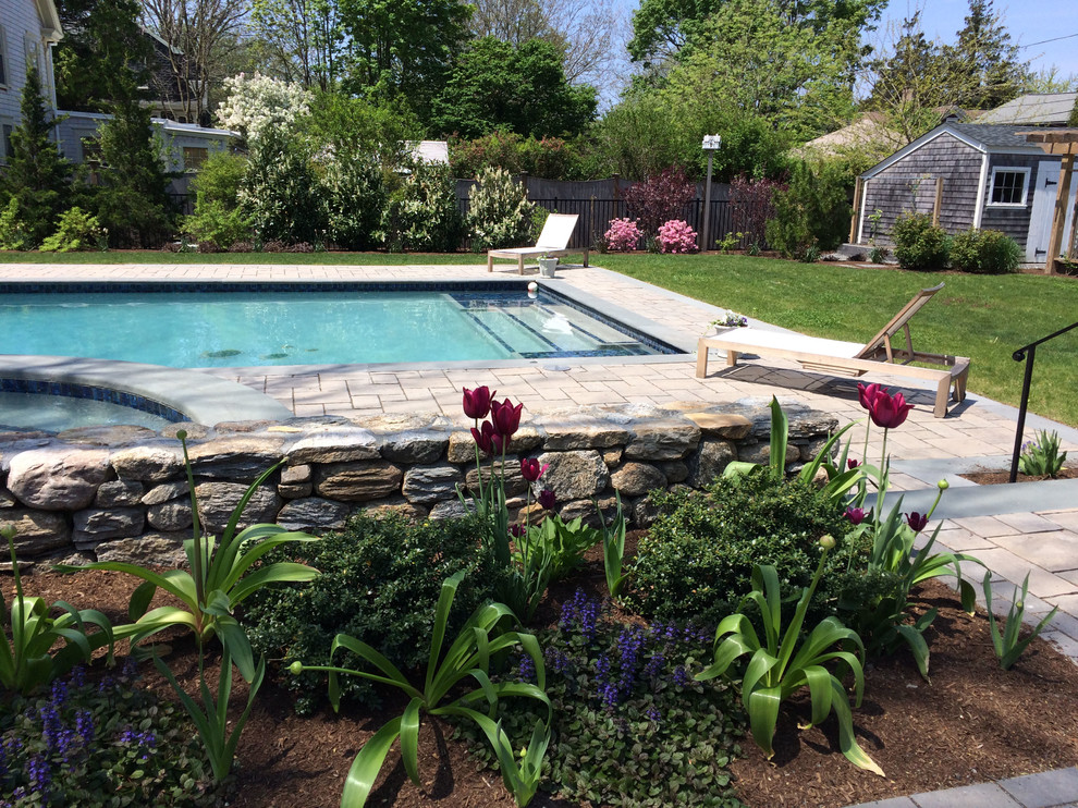 Modelo de piscina tradicional renovada de tamaño medio rectangular en patio lateral con adoquines de hormigón