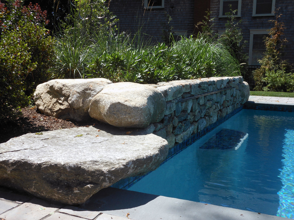 Réalisation d'une grande piscine latérale tradition rectangle avec un point d'eau et des pavés en béton.