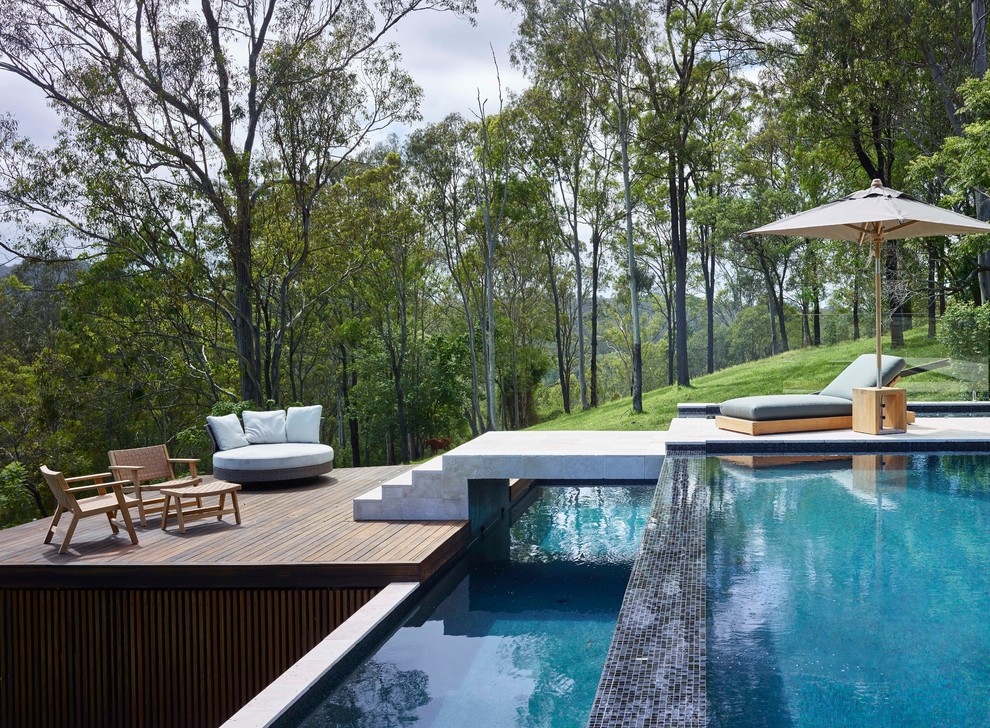 Modelo de piscina infinita moderna rectangular en patio trasero con entablado