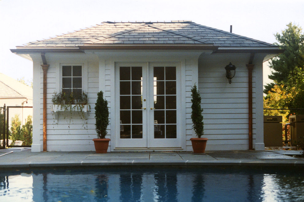 Imagen de casa de la piscina y piscina clásica grande en patio trasero con adoquines de piedra natural