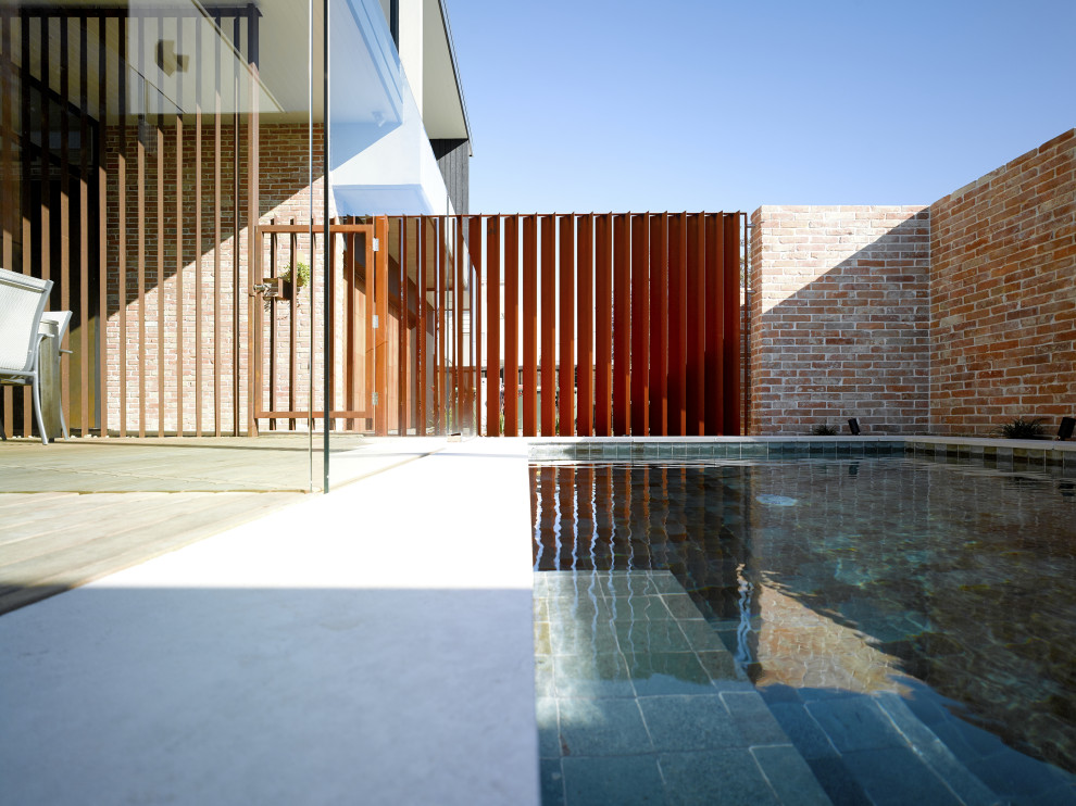 Foto de piscina elevada industrial pequeña rectangular en patio trasero con privacidad y adoquines de piedra natural