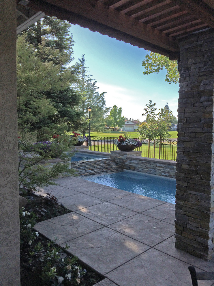 Ispirazione per una grande piscina classica rettangolare dietro casa con una vasca idromassaggio e cemento stampato