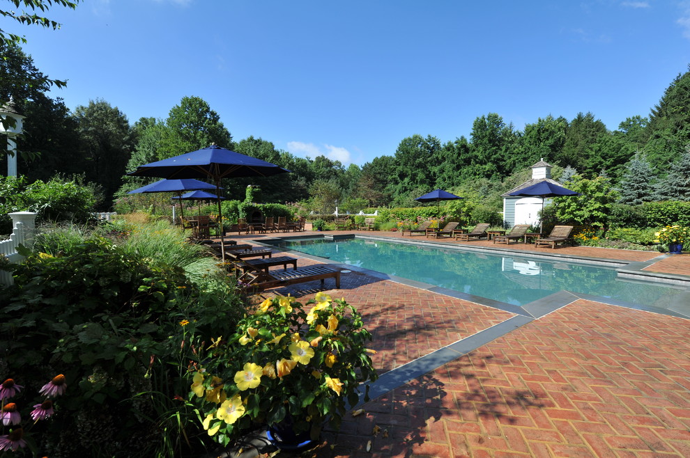 Foto de piscina alargada clásica de tamaño medio rectangular en patio trasero con adoquines de ladrillo