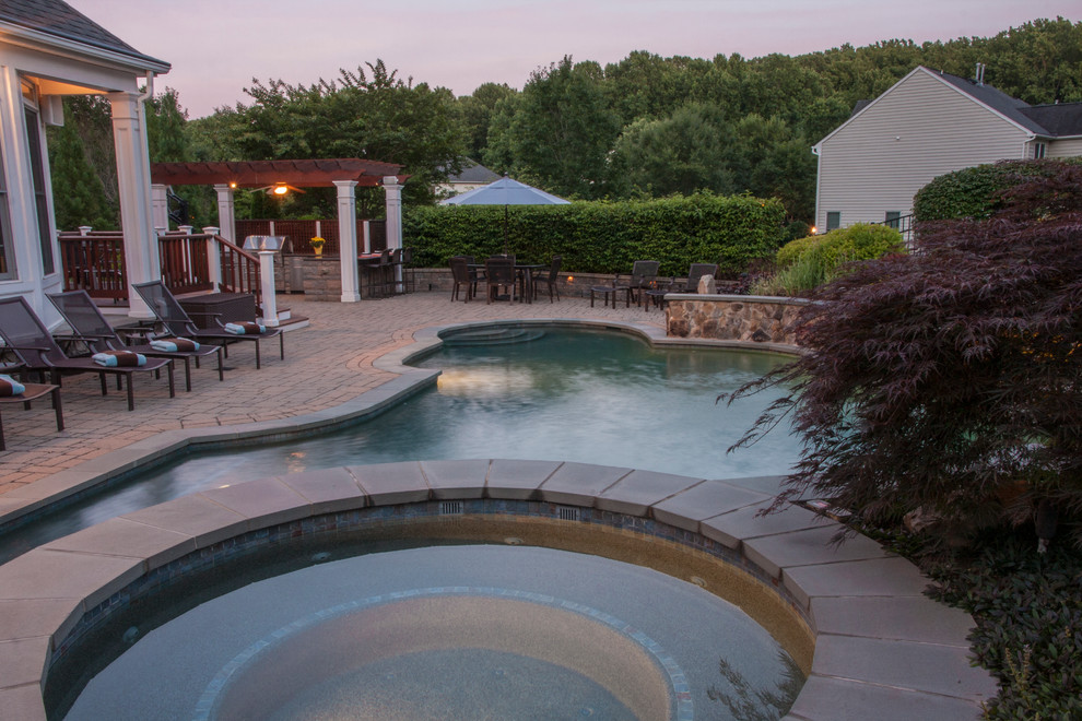 Diseño de piscinas y jacuzzis alargados clásicos de tamaño medio a medida en patio trasero con adoquines de piedra natural