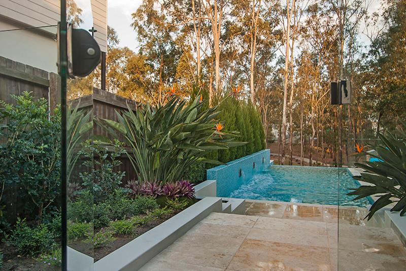 Foto de piscina con fuente elevada actual de tamaño medio rectangular en patio trasero con suelo de baldosas