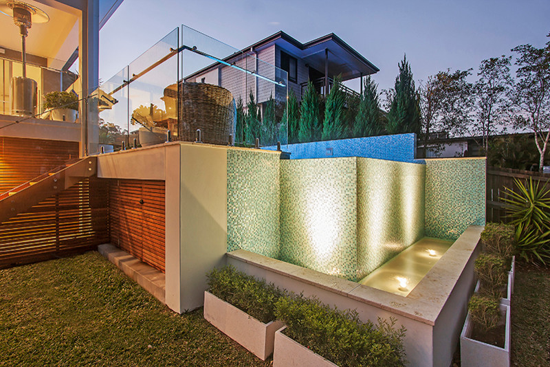 Foto de piscina con fuente elevada contemporánea de tamaño medio rectangular en patio trasero con suelo de baldosas