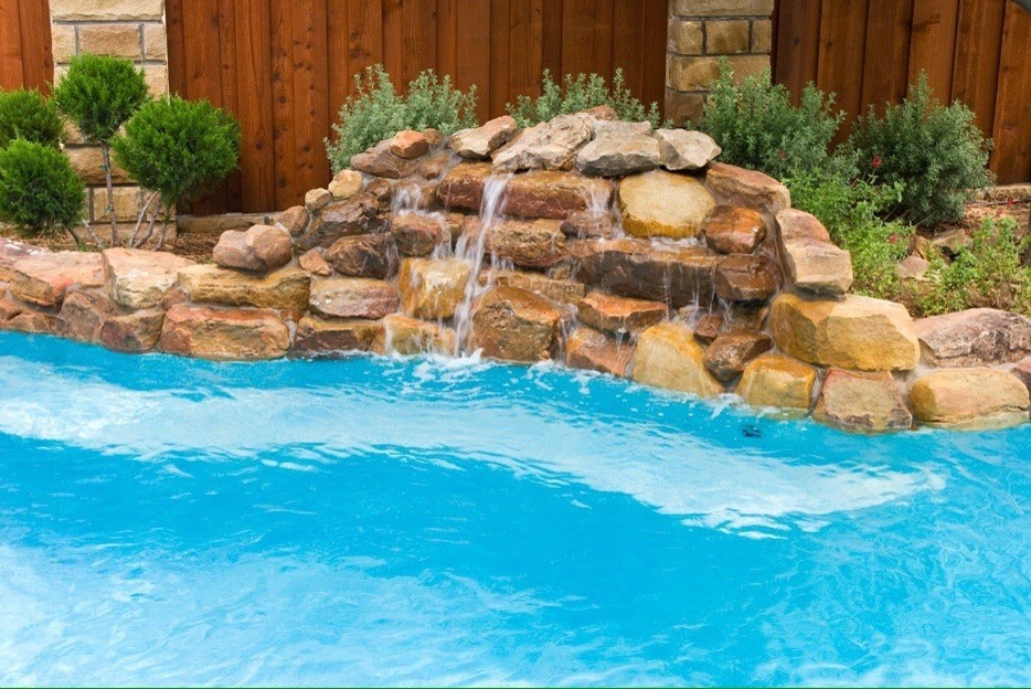 Imagen de piscina infinita clásica de tamaño medio a medida en patio trasero con adoquines de hormigón
