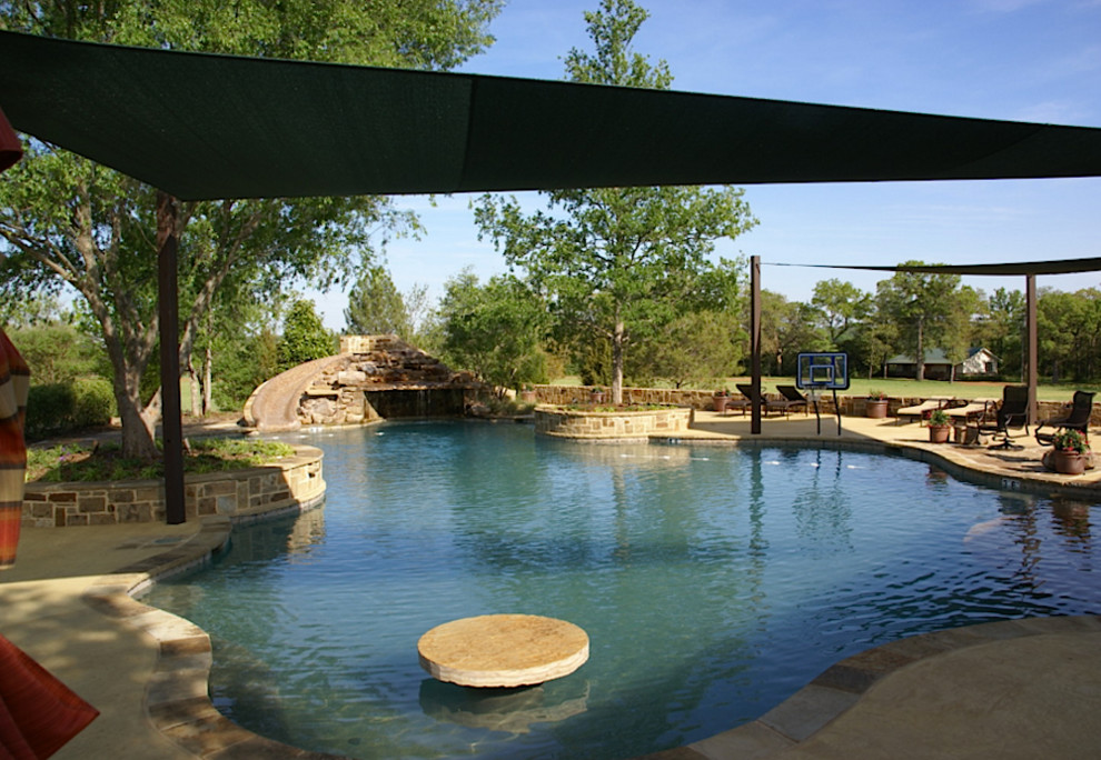 Ejemplo de piscina con tobogán clásica renovada grande a medida en patio trasero con adoquines de hormigón