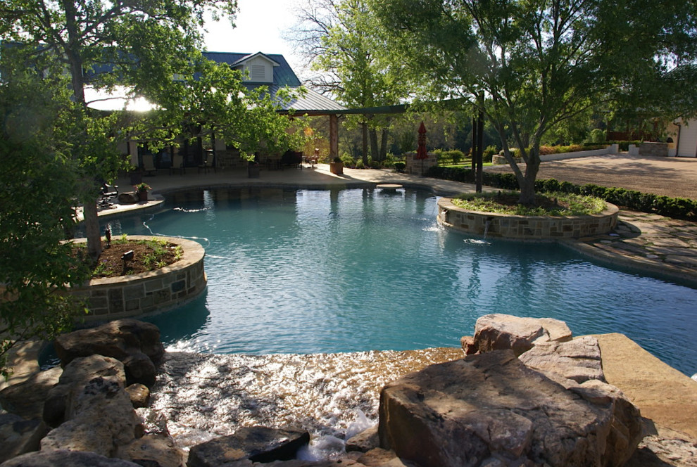 Ejemplo de piscina con tobogán clásica renovada grande a medida en patio trasero con adoquines de hormigón