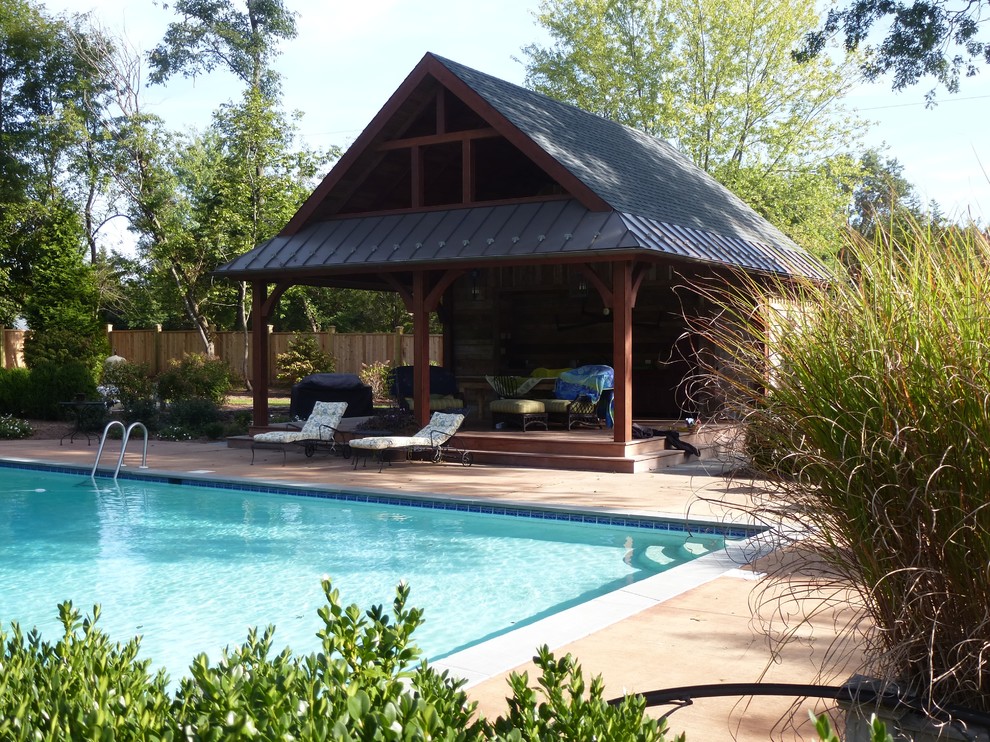 Esempio di una grande piscina monocorsia rustica rettangolare dietro casa con una dépendance a bordo piscina e lastre di cemento