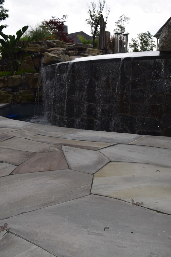 Esempio di una piscina a sfioro infinito minimalista personalizzata di medie dimensioni e dietro casa con fontane e pavimentazioni in pietra naturale