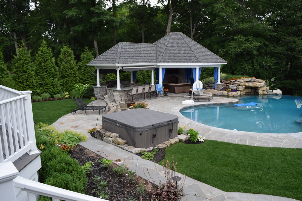 Modelo de piscina con fuente infinita moderna de tamaño medio a medida en patio trasero con adoquines de piedra natural