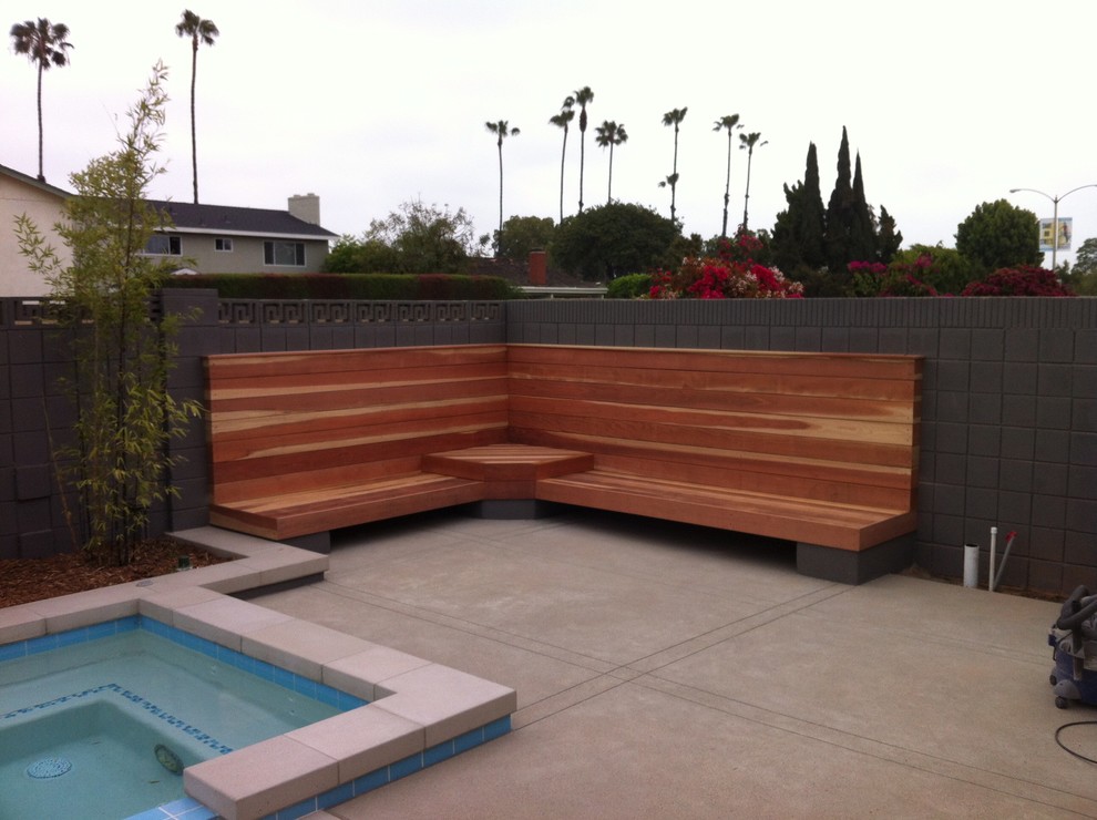 Ejemplo de piscina elevada actual pequeña rectangular en patio trasero con losas de hormigón