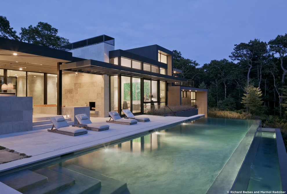 Large minimalist backyard stamped concrete and rectangular infinity pool fountain photo in New York