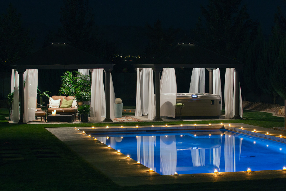 Modelo de piscinas y jacuzzis naturales clásicos renovados grandes rectangulares en patio trasero con losas de hormigón