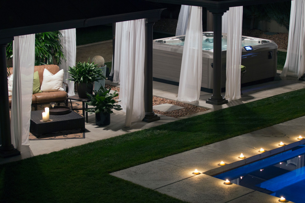 Immagine di una piscina monocorsia minimal rettangolare di medie dimensioni e dietro casa con una vasca idromassaggio e lastre di cemento