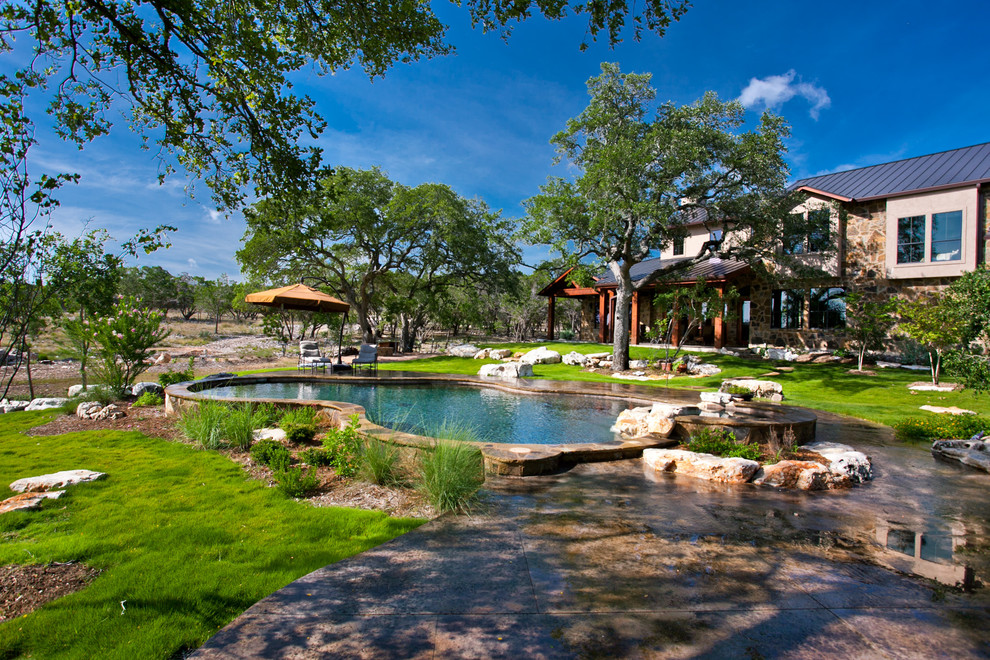 Diseño de piscina con fuente natural rural grande a medida en patio trasero con losas de hormigón