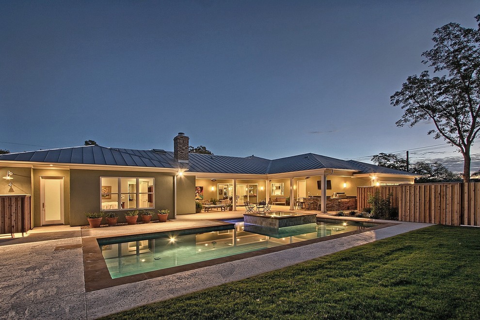 Ejemplo de piscinas y jacuzzis infinitos de estilo americano de tamaño medio en forma de L en patio trasero con losas de hormigón