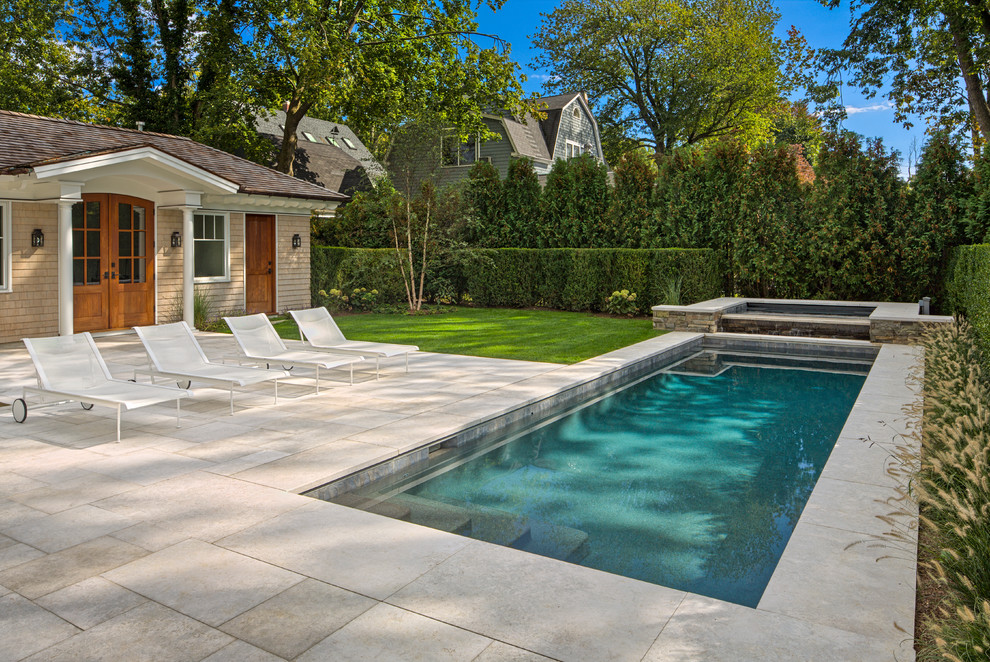 Foto di una grande piscina monocorsia stile marino rettangolare dietro casa con una vasca idromassaggio e pavimentazioni in pietra naturale