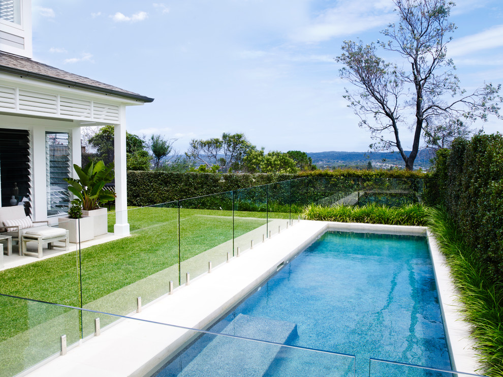 Ejemplo de piscina costera de tamaño medio rectangular en patio trasero con adoquines de piedra natural