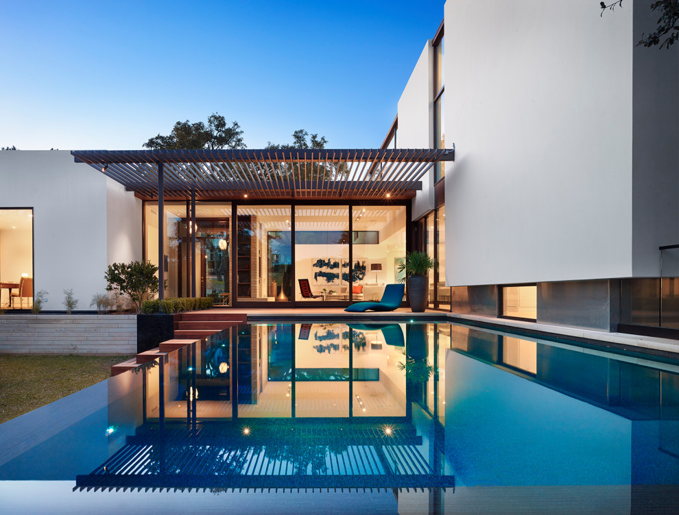 Esempio di una grande piscina a sfioro infinito minimalista rettangolare dietro casa con fontane e pedane
