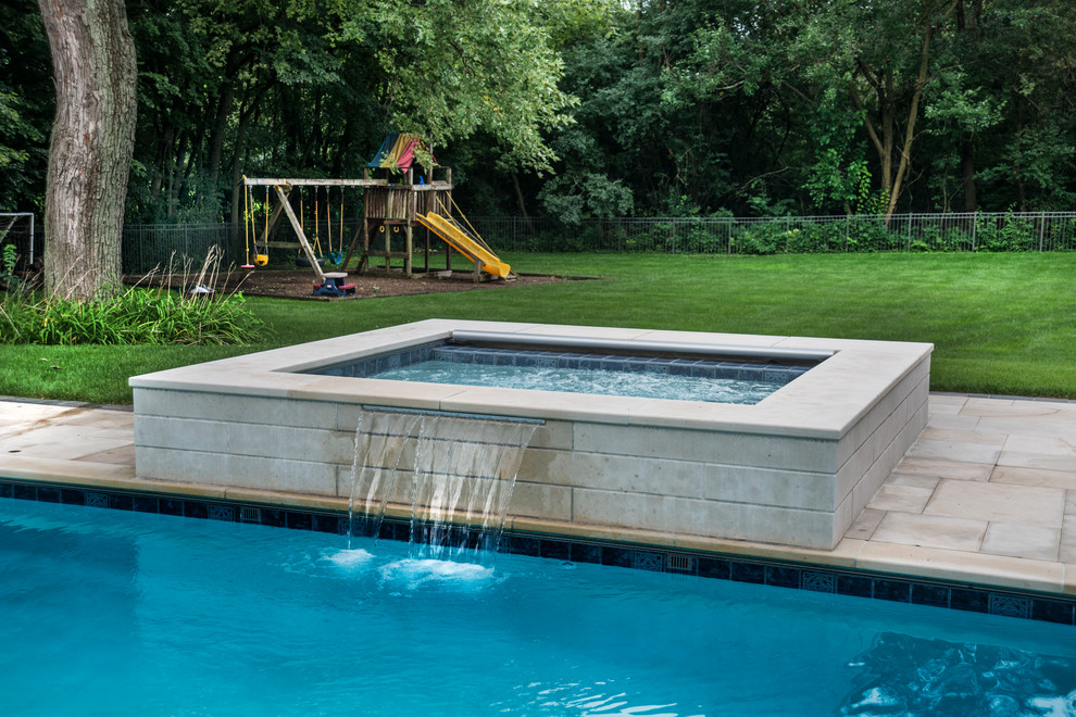 Modelo de piscinas y jacuzzis alargados tradicionales de tamaño medio rectangulares en patio trasero con adoquines de hormigón