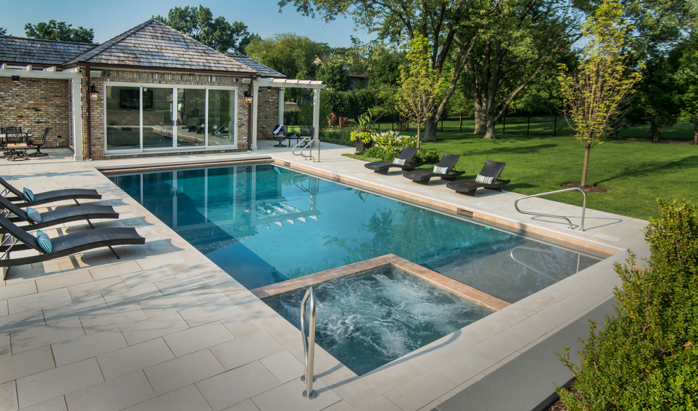 Immagine di una piscina monocorsia tradizionale rettangolare di medie dimensioni e dietro casa con una vasca idromassaggio e pavimentazioni in pietra naturale