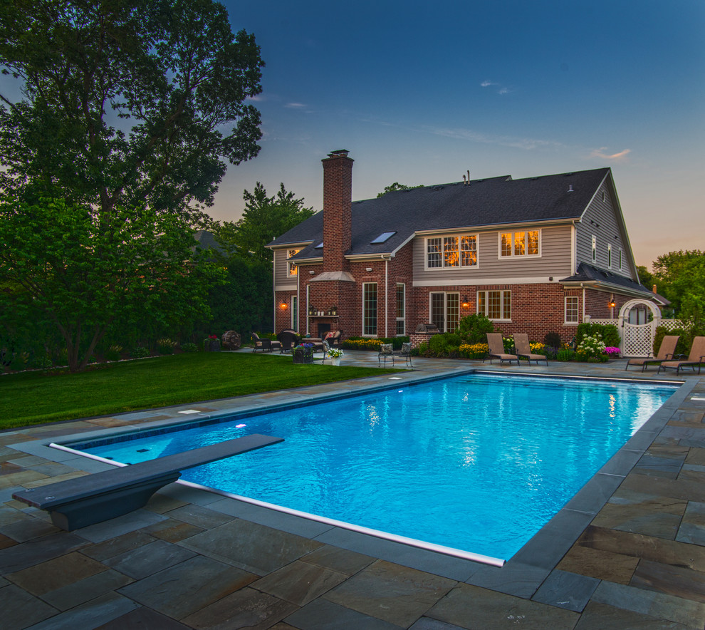 Foto de piscina alargada clásica de tamaño medio rectangular en patio trasero con adoquines de piedra natural