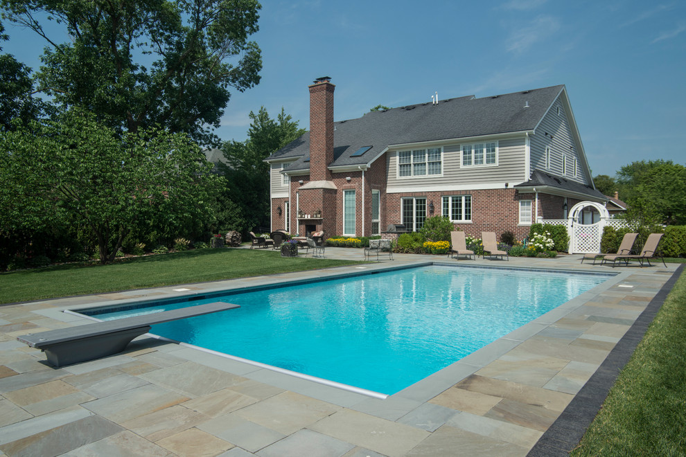 Diseño de piscina alargada clásica de tamaño medio rectangular en patio trasero con adoquines de piedra natural