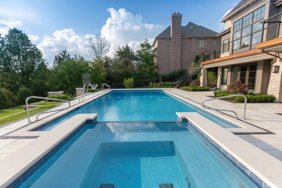 Foto di una piscina monocorsia classica rettangolare di medie dimensioni e dietro casa con una vasca idromassaggio e pavimentazioni in pietra naturale