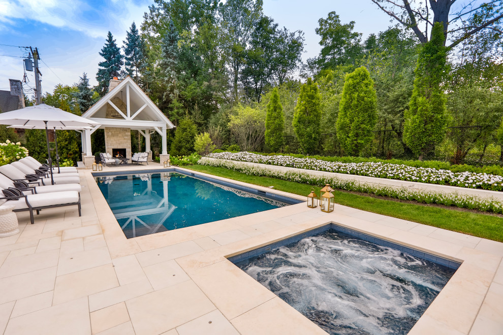 Ispirazione per una piscina monocorsia chic rettangolare di medie dimensioni e dietro casa con una vasca idromassaggio e pavimentazioni in pietra naturale