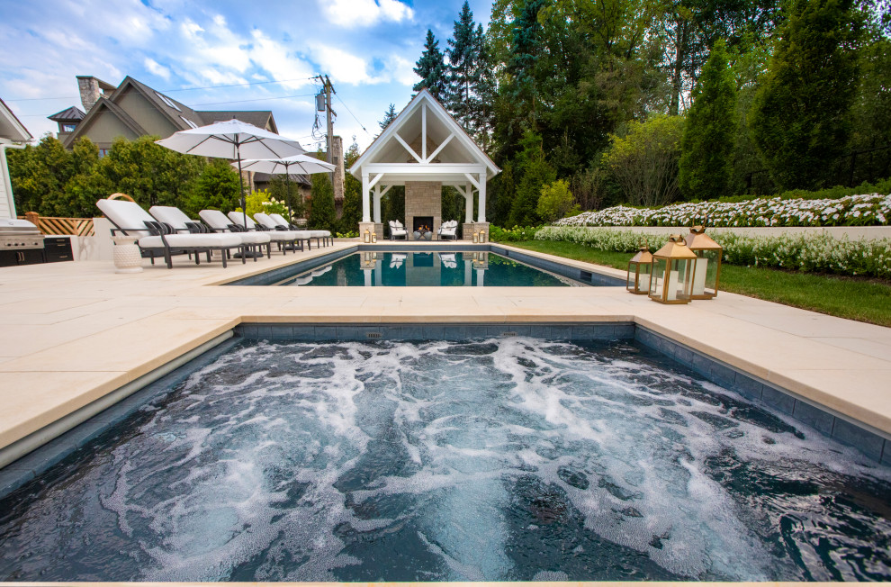 Esempio di una piscina monocorsia classica rettangolare di medie dimensioni e dietro casa con una vasca idromassaggio e pavimentazioni in pietra naturale