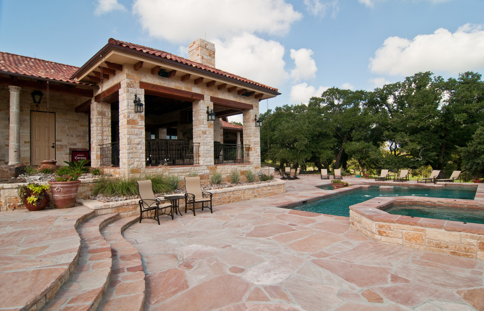 Inspiration for a large rustic backyard stone and custom-shaped infinity hot tub remodel in Houston