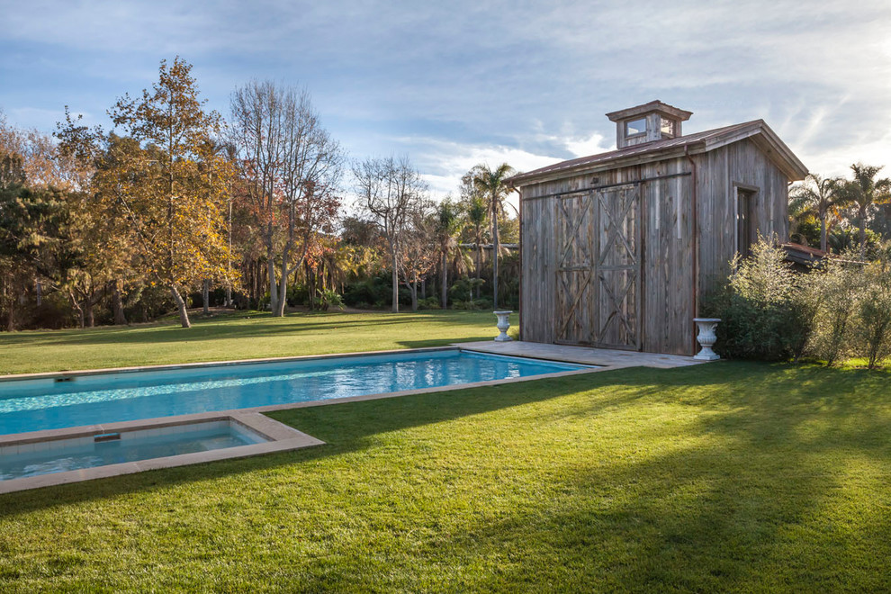 На фото: спортивный, прямоугольный бассейн на заднем дворе в стиле кантри с домиком у бассейна и покрытием из каменной брусчатки