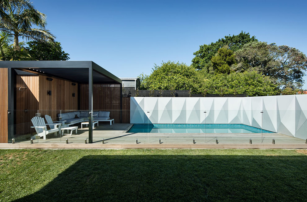 Cette image montre une piscine vintage de taille moyenne et rectangle avec des solutions pour vis-à-vis, une cour et une terrasse en bois.