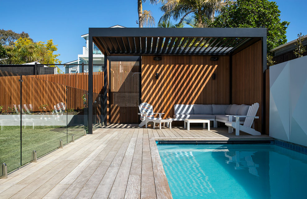Пример оригинального дизайна: прямоугольный бассейн среднего размера на внутреннем дворе в стиле ретро с домиком у бассейна и настилом
