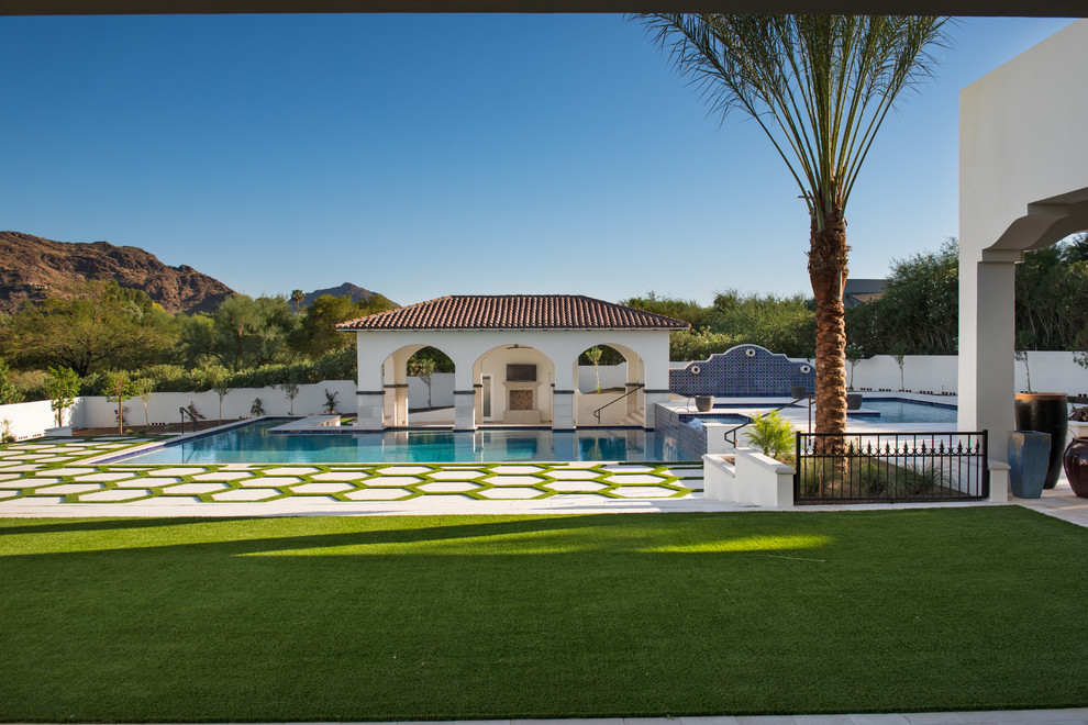 Photo of a large contemporary back l-shaped above ground swimming pool in Phoenix with a water feature and tiled flooring.