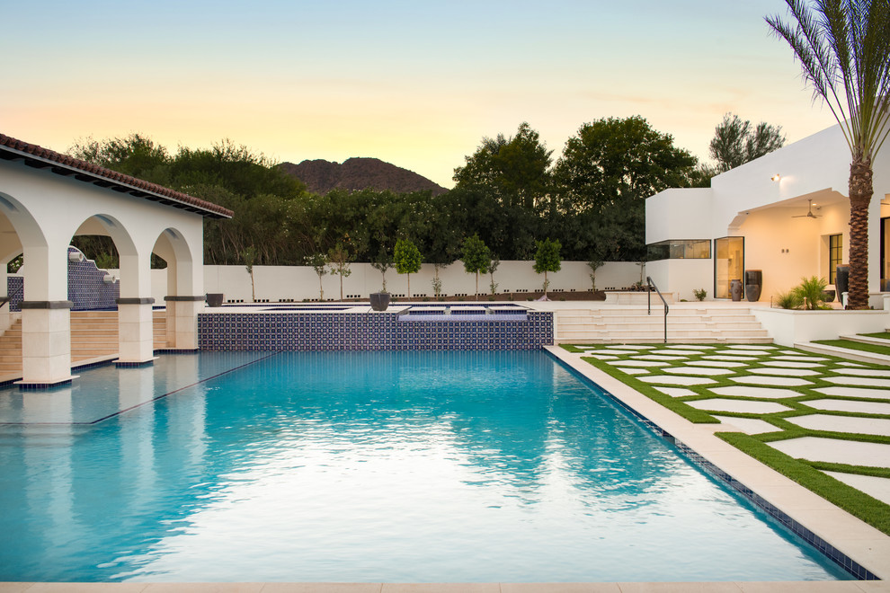 Immagine di una grande piscina fuori terra design a "L" dietro casa con fontane e piastrelle
