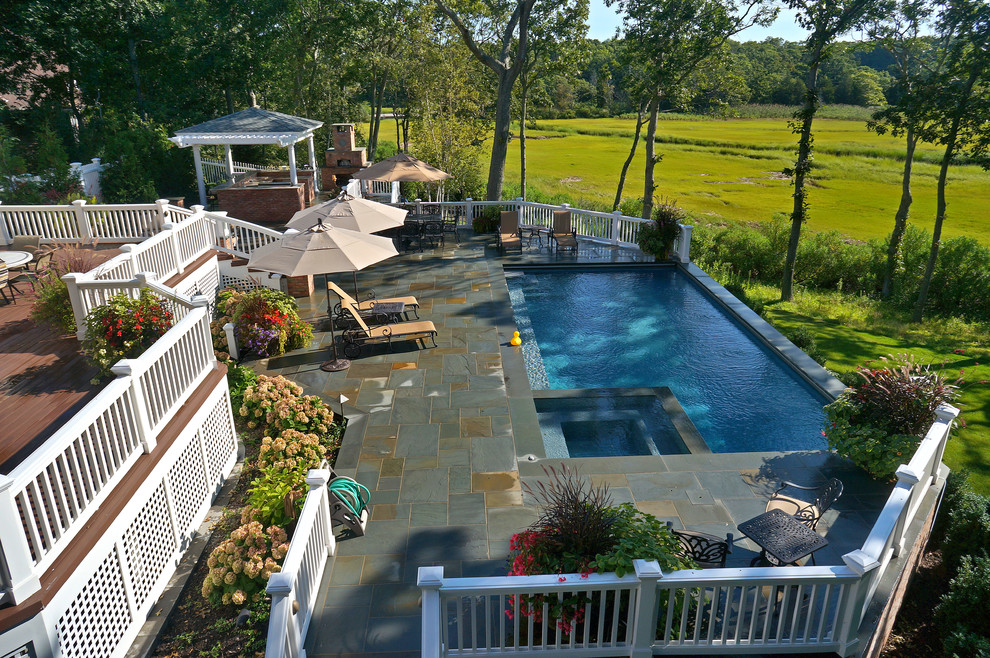 На фото: спортивный, угловой бассейн среднего размера на заднем дворе в классическом стиле с джакузи и покрытием из каменной брусчатки