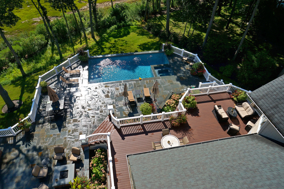 Imagen de piscinas y jacuzzis alargados clásicos de tamaño medio en forma de L en patio trasero con adoquines de piedra natural