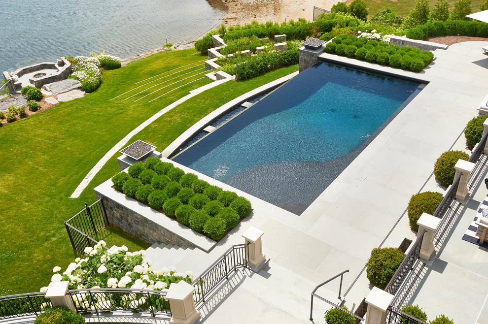 Large elegant backyard stone and rectangular infinity pool house photo in New York