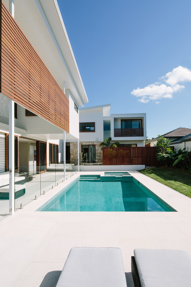 На фото: прямоугольный бассейн на заднем дворе в современном стиле с джакузи