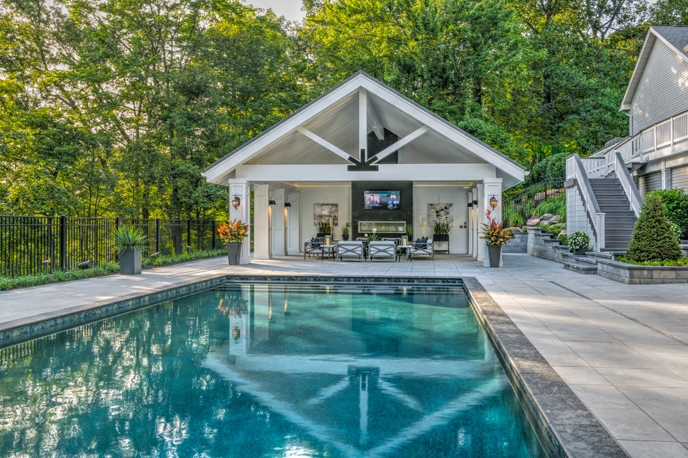 Modelo de casa de la piscina y piscina alargada clásica renovada grande rectangular en patio trasero con adoquines de hormigón