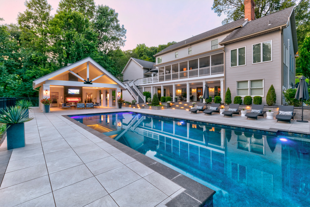 Diseño de casa de la piscina y piscina alargada clásica renovada grande rectangular en patio trasero con adoquines de hormigón
